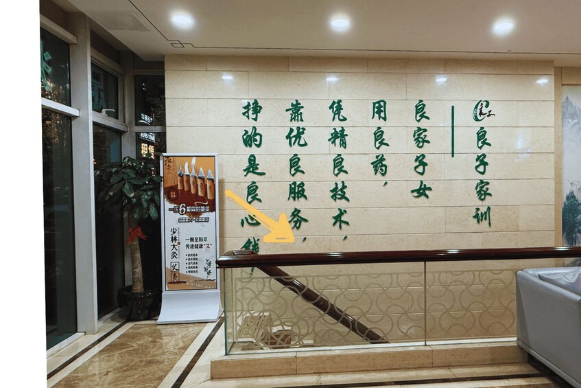 A wall with Chinese characters, a poster with a red ribbon, and a staircase with a railing. 2
