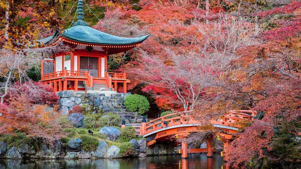 A traditional Japanese pagoda with a curved roof, surrounded by autumn foliage and a stone bridge. 5