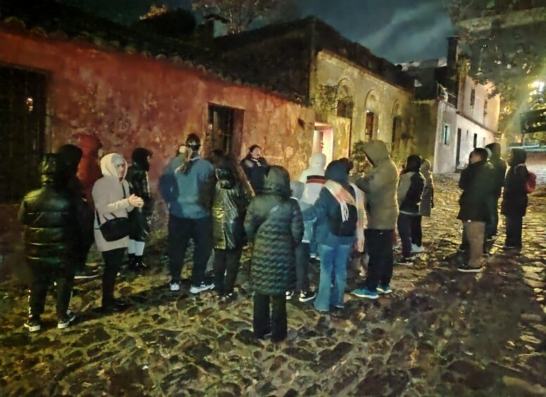 A group of people standing on a cobblestone street at night. 5