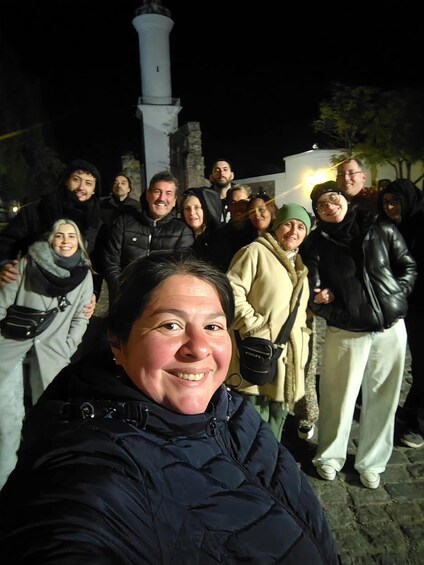 A group of people standing in front of a lighthouse at night. 1