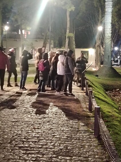 A group of people gathered on a cobblestone path at night. 3