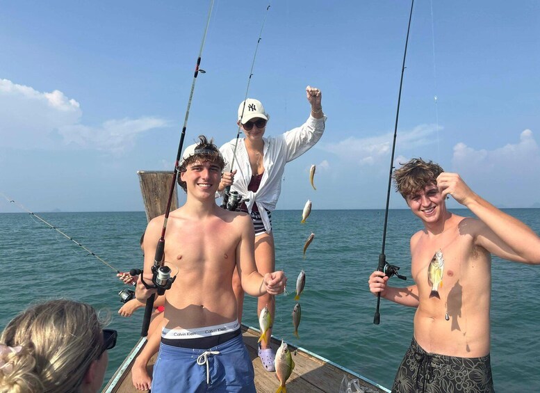 Three people on a boat with fishing rods, holding fish. 1