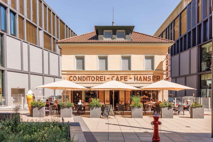 A cafe named 'CONDITOREI - CAFE - HANSER' with outdoor seating and umbrellas. 5