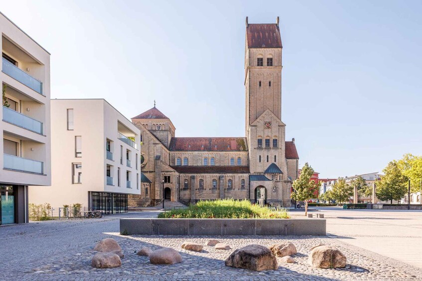 A historic church with a tall tower and a modern building beside it. 1