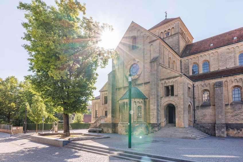 A historic building with a clock tower, surrounded by trees and a paved courtyard. 4