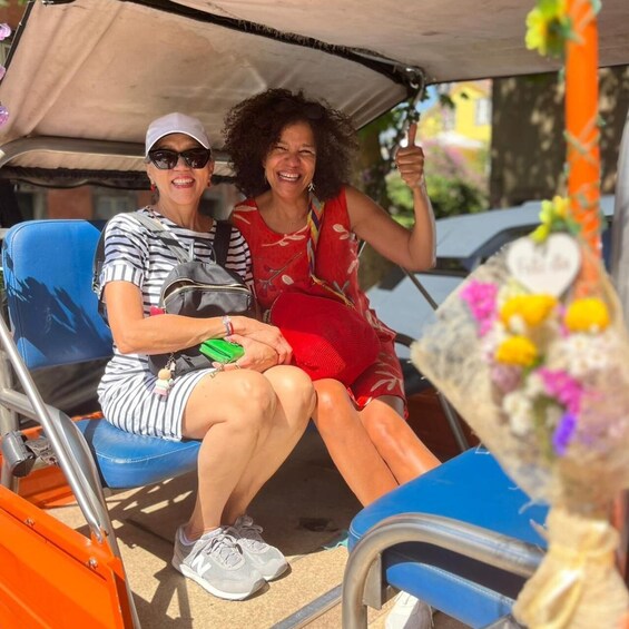 Two people sitting on a blue chair under a canopy, holding a bouquet of flowers. 1