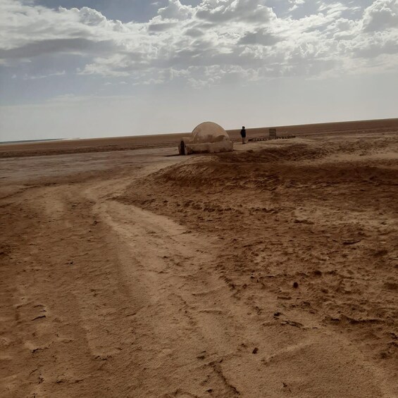 A desert landscape with a large, dome-shaped structure and a person standing nearby. 2