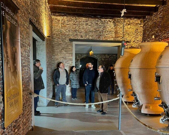 A group of people inside a building with brick walls and a large wooden barrel. 1