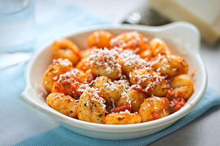 A bowl of gnocchi with tomato sauce and grated cheese. 5