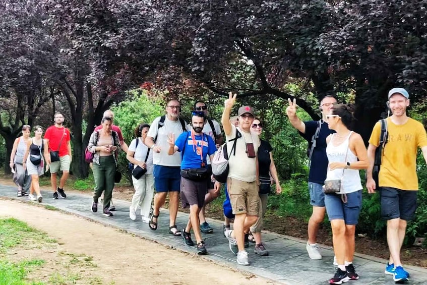 A group of people walking on a paved path in a park with trees and greenery. 2