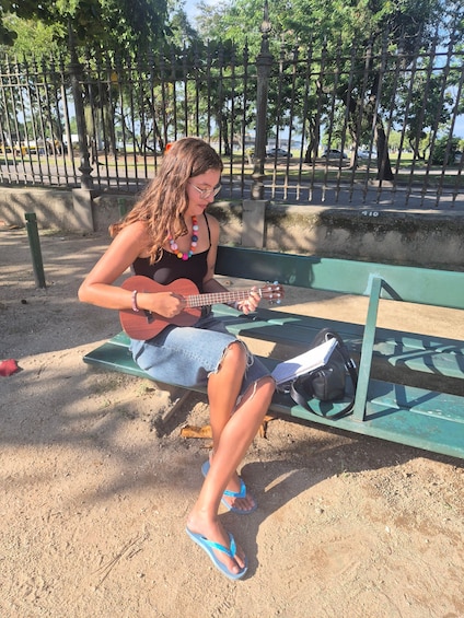 A person sitting on a bench playing a guitar. 1