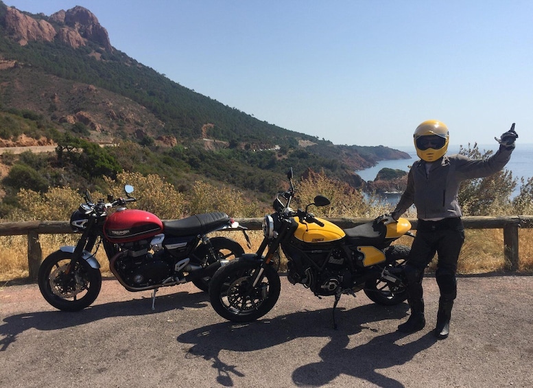 Two motorcycles parked on a roadside with a scenic view of mountains and a body of water in the background. 5