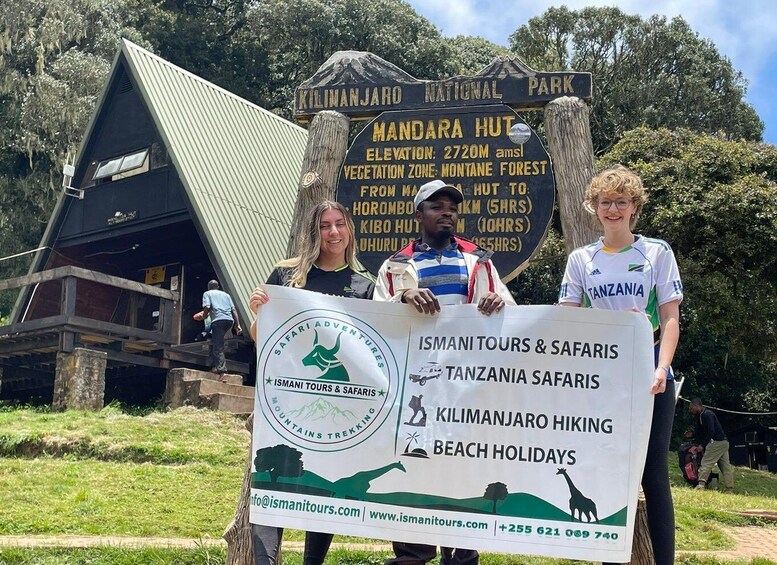 A signboard for Kilimanjaro National Park with a Mandara Hut, elevation details, and hiking times. 3
