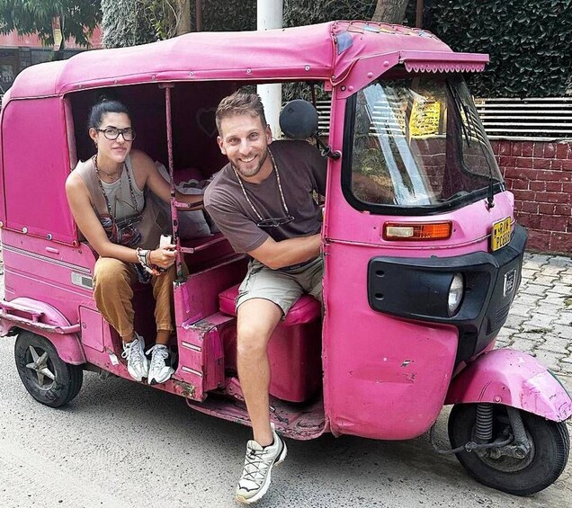 Two people sitting in a pink auto-rickshaw. 3