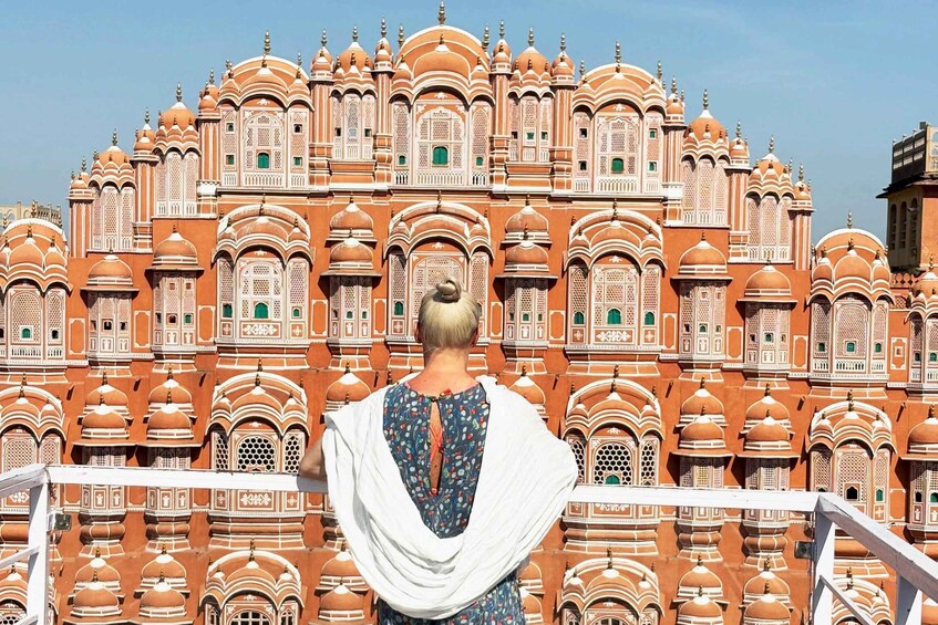 A person standing in front of a large, ornate building with multiple domes and intricate architectural details. 1