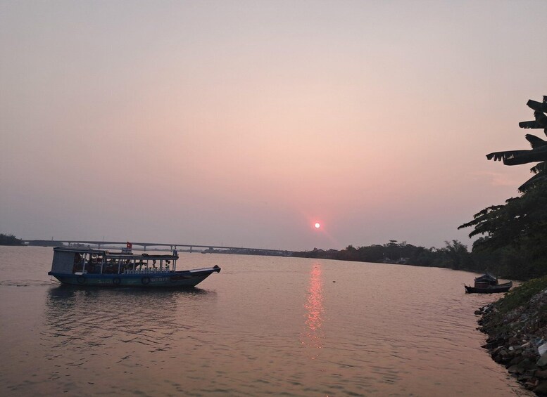 A sunset over a river with a boat and a bridge in the background. 1