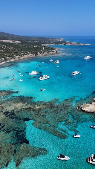 A coastal area with clear turquoise waters, numerous boats, and a hilly landscape in the background. 1