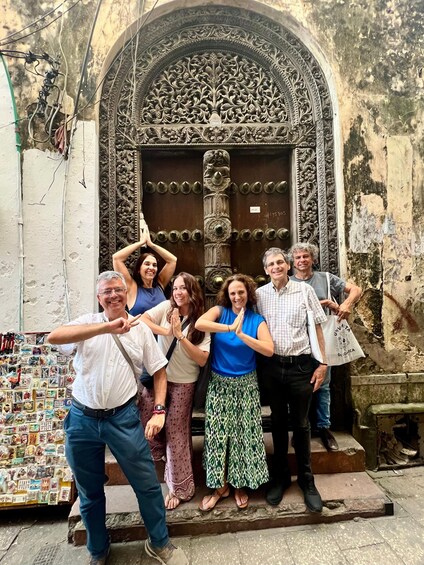 A group of people posing in front of an ornate door with intricate carvings and a sign reading 'U.S. 15 100'. 2