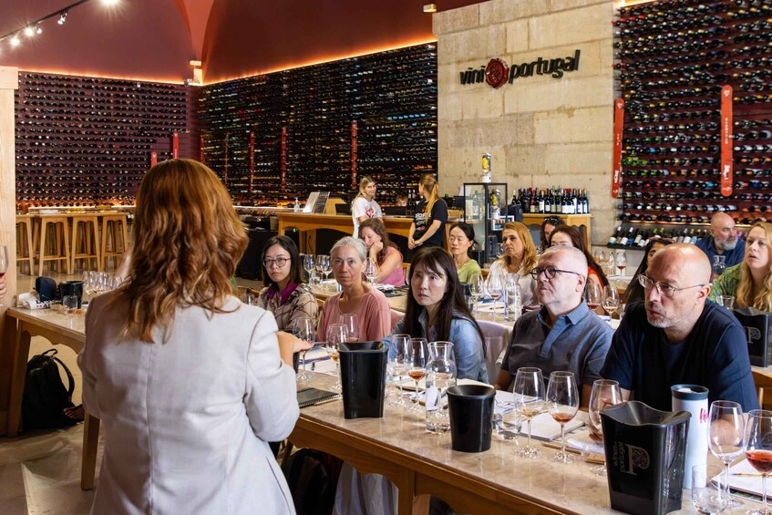 A wine tasting event in a bar with a large wine wall and several patrons seated at tables. 5