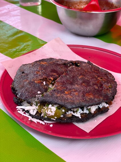 A sandwich on a red plate with a green tablecloth. 5