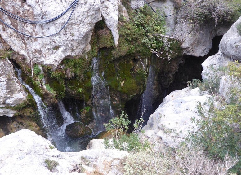 A rocky landscape with a waterfall cascading down a cliff, surrounded by moss and small plants. 5