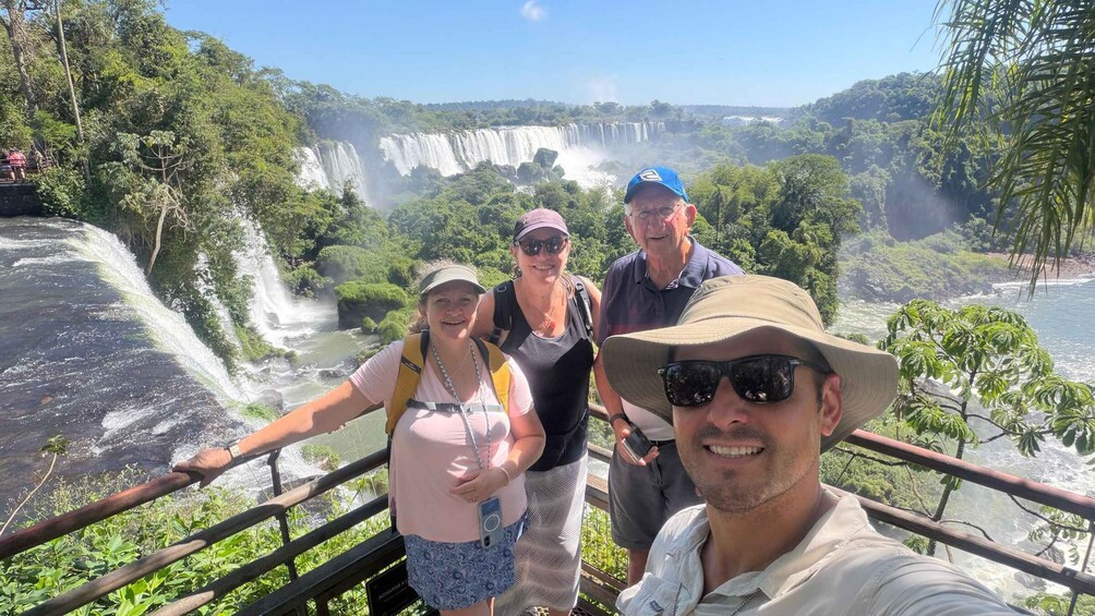 A group of people standing on a railing overlooking a waterfall. 1