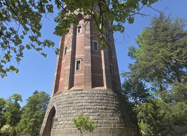 A tall brick tower with arched windows, surrounded by trees. 5