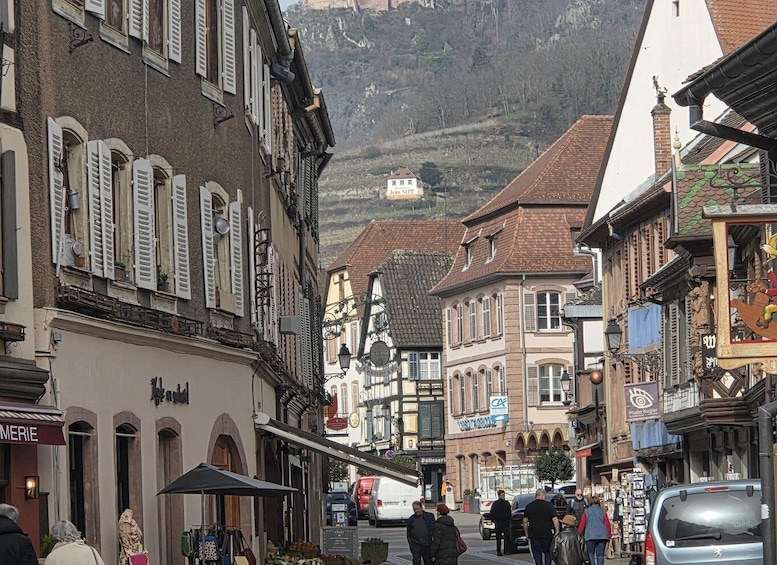 A bustling European street with traditional architecture, a mountain backdrop, and a variety of shops and cafes. 4