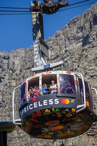 A cable car with passengers, labeled "PRICELESS," against a rocky mountain backdrop. 5
