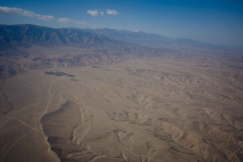A vast desert landscape with undulating terrain and distant mountain ranges. 1