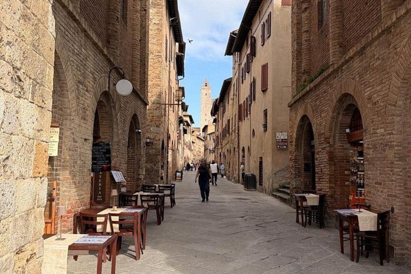 Une rue étroite bordée d’immeubles en briques, avec des tables et des chaises disposées pour permettre de déjeuner ou de dîner en plein air. 5