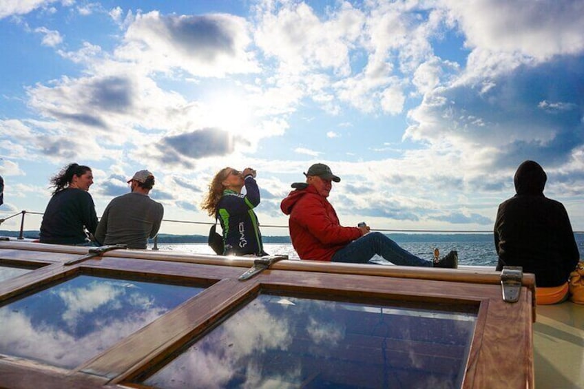 People sitting on a boat deck with a view of the ocean and sky. 1