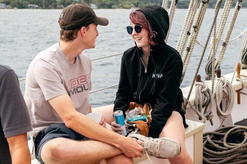 Two people on a boat, one holding a drink and the other holding a bag. 4