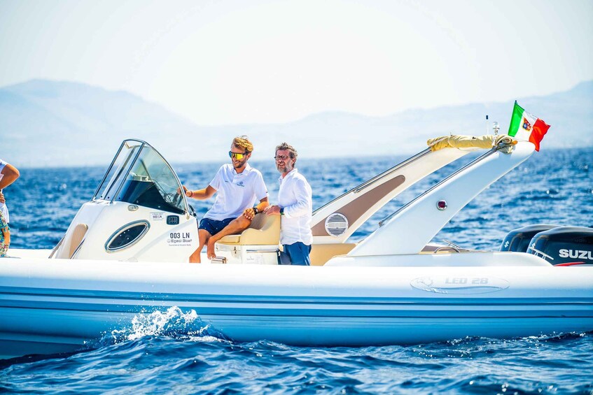 A boat with a flag, a person in a white shirt, and another in a white shirt and shorts. 1