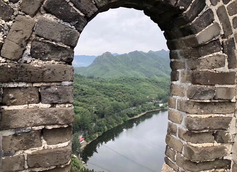 A stone archway with a view of a river and mountains. 1