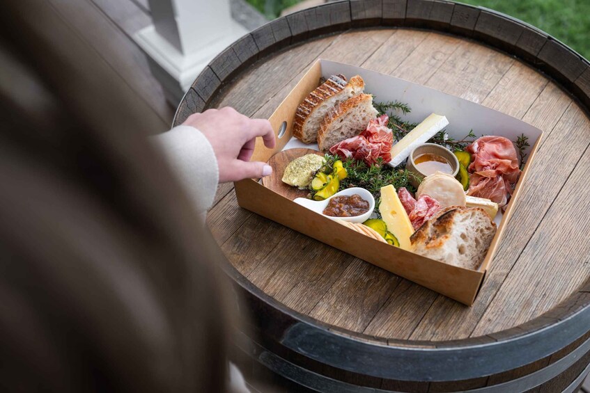A charcuterie board with various meats, cheeses, and bread on a wooden barrel. 3