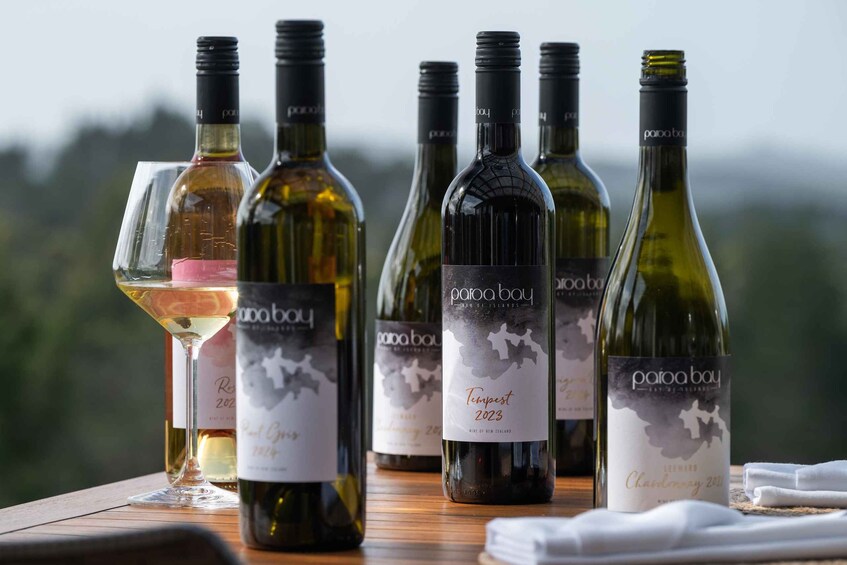 Several wine bottles and glasses on a wooden table with a blurred natural background. 5