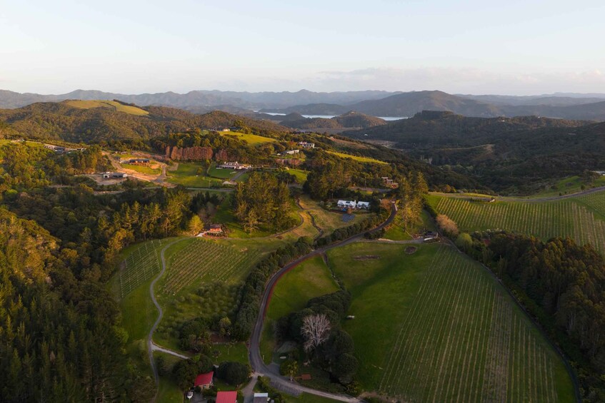 A rural landscape with rolling hills, a winding road, and scattered buildings. 1