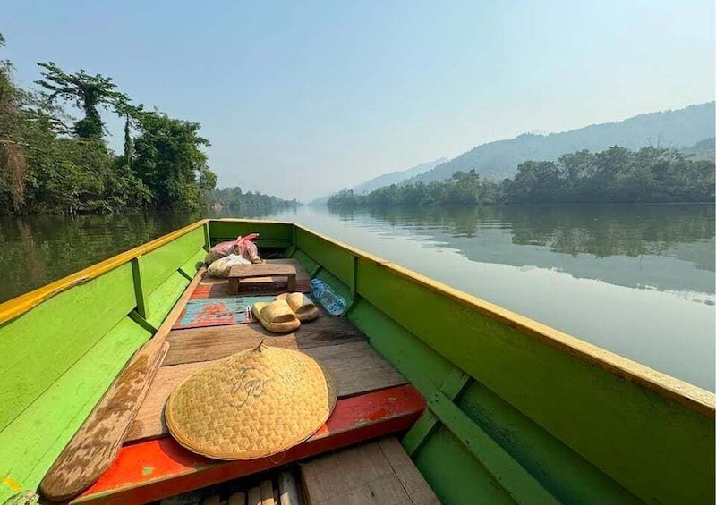 A green boat on calm water with a hat and sandals on the deck. 4