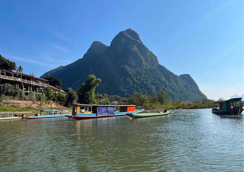 A river with boats, a mountain, and a building on the left. 3