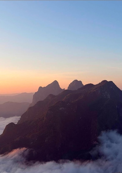 A mountain range with peaks silhouetted against a sunset sky. 1