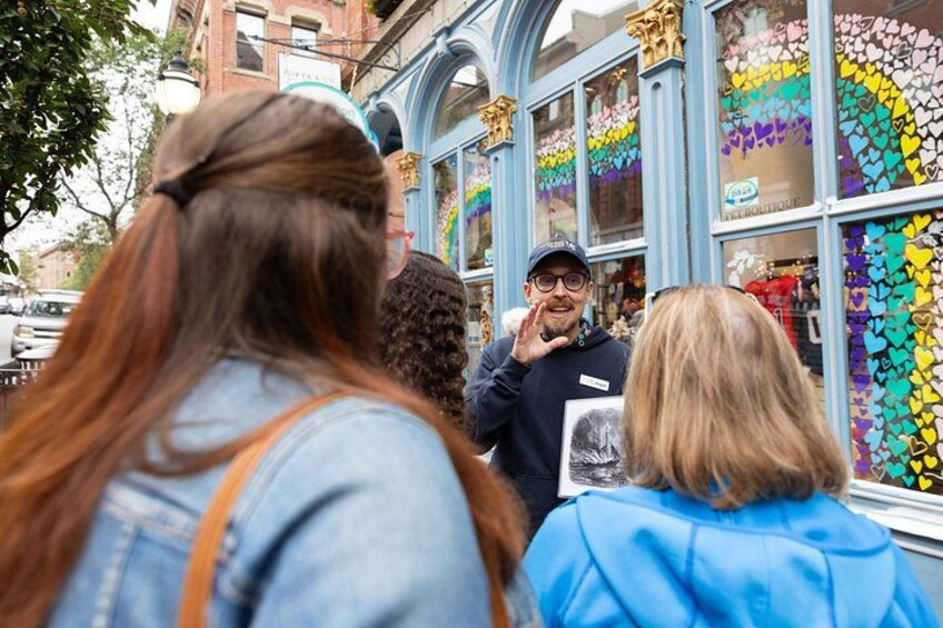 Escena callejera con gente caminando y una tienda decorada con corazones de colores. 2