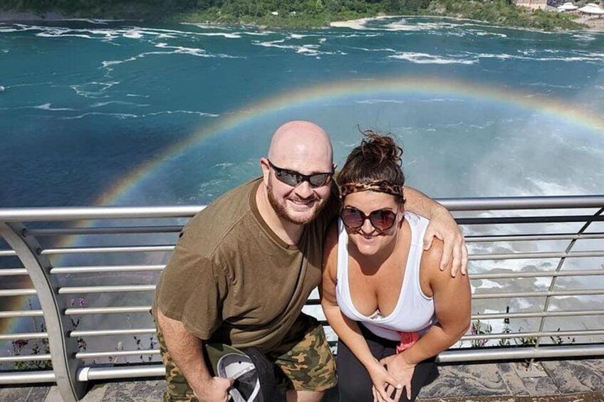 Een man en een vrouw zitten op een metalen hek met een regenboog op de achtergrond. 5