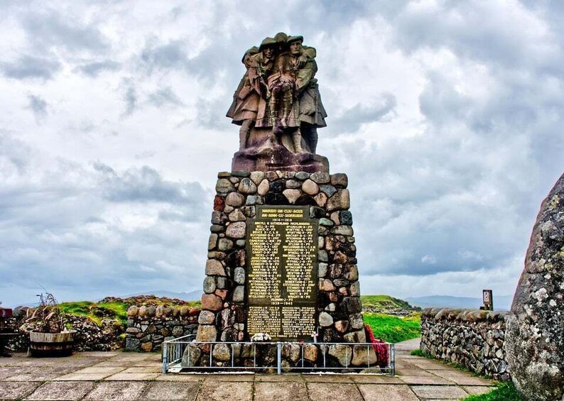 A stone monument with a statue and an inscription plaque. 2