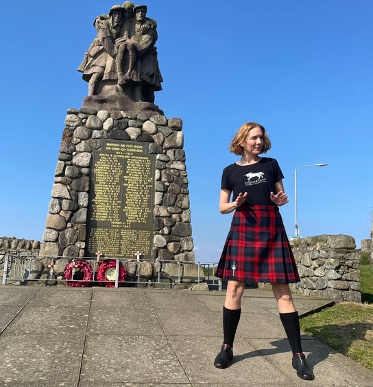 A person standing in front of a stone monument with inscriptions and a statue. 4