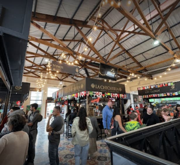 A crowded indoor market with wooden beams and hanging lights. 2