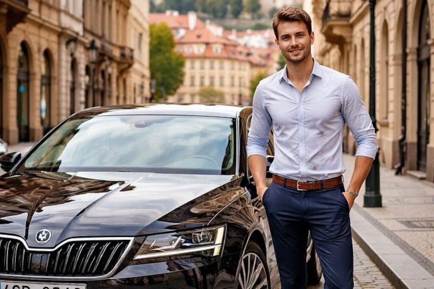 Un uomo in piedi accanto a un'auto nera su una strada cittadina, con edifici storici sullo sfondo. 2