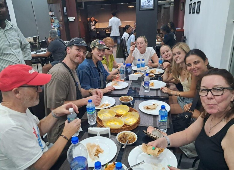 A group of people sitting around a table with food and drinks, in a casual dining setting. 1