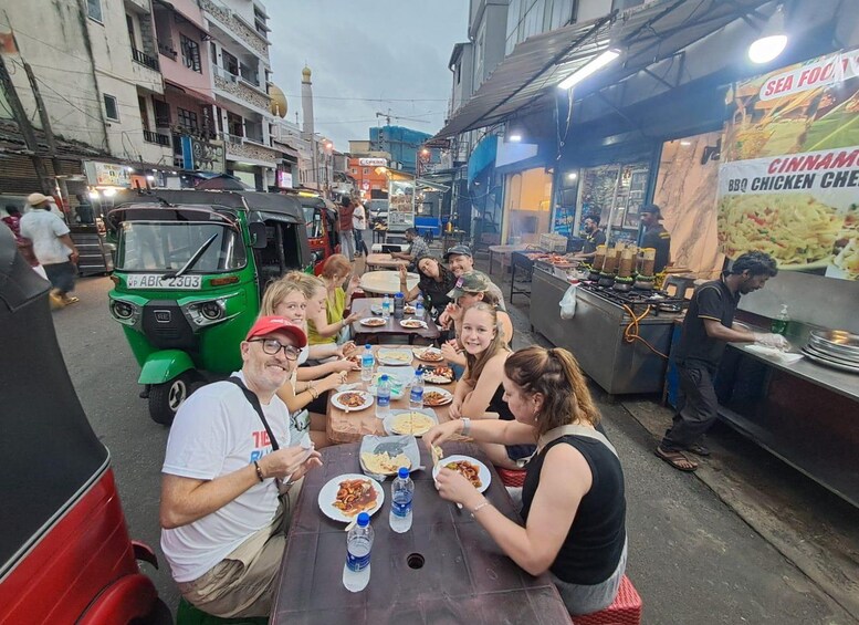 A group of people dining outdoors at a street food stall. 2