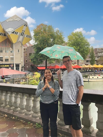 Two people standing by a canal with a modern building and a green umbrella in the background. 5